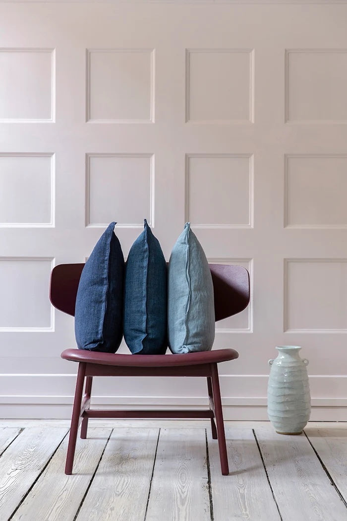 Tourmaline blue linen cushion shown from the side in a row of three blue cushions on a chair