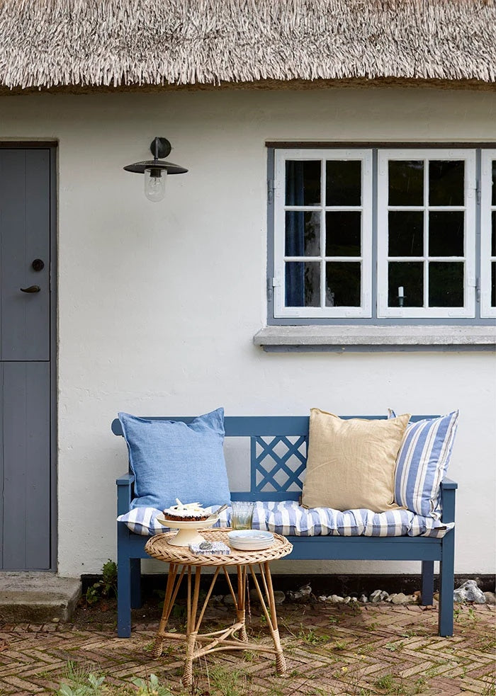 Tourmaline blue linen cushion on a painted wooden garden bench beside a neutral cushion