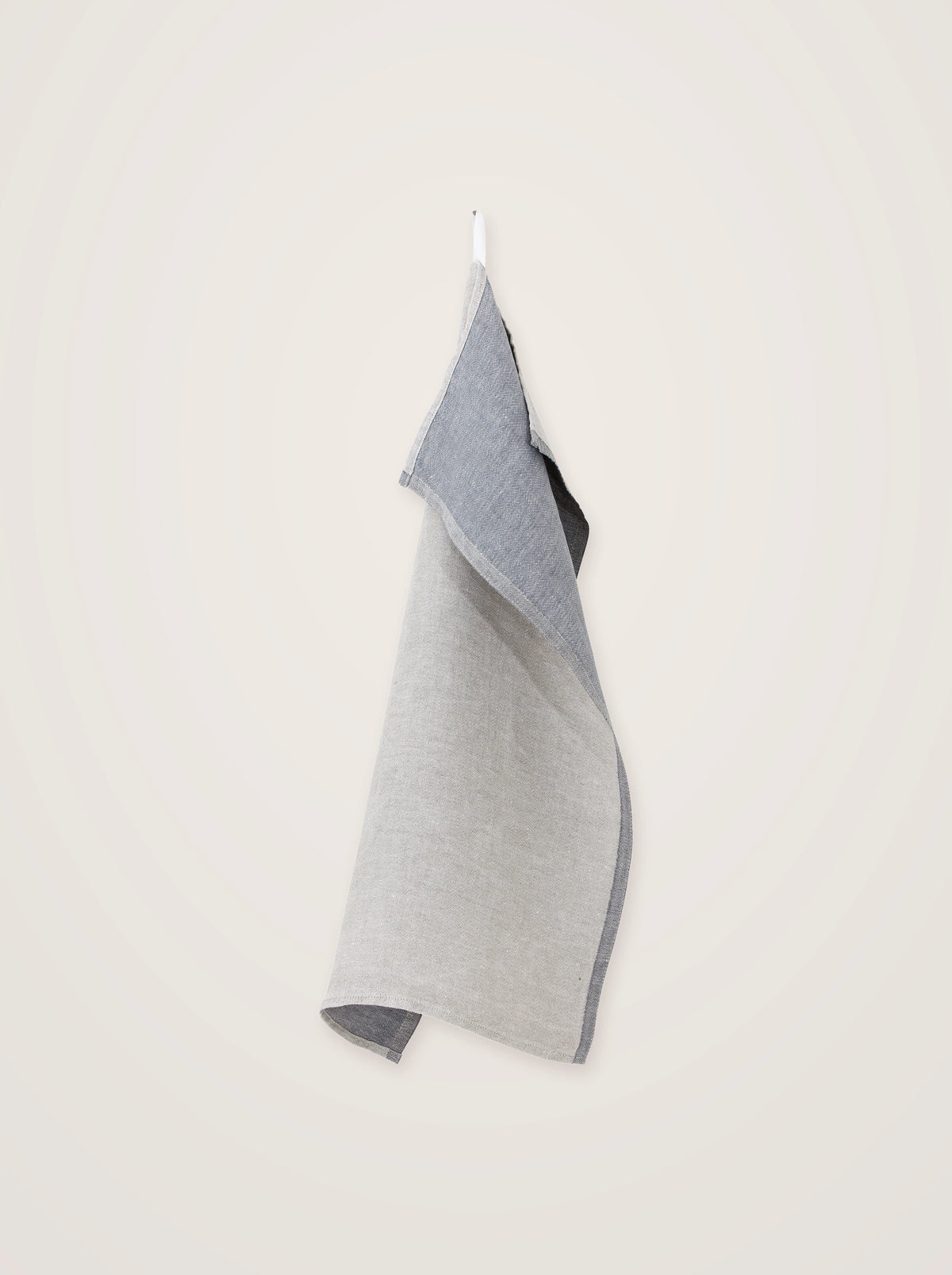 Two-tone washed linen towel in light and dark grey, hanging from an integrated loop