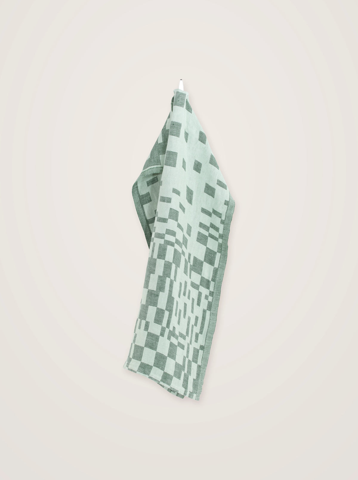 Mint washed linen towel hanging by its loop, showing the drape and geometric check pattern