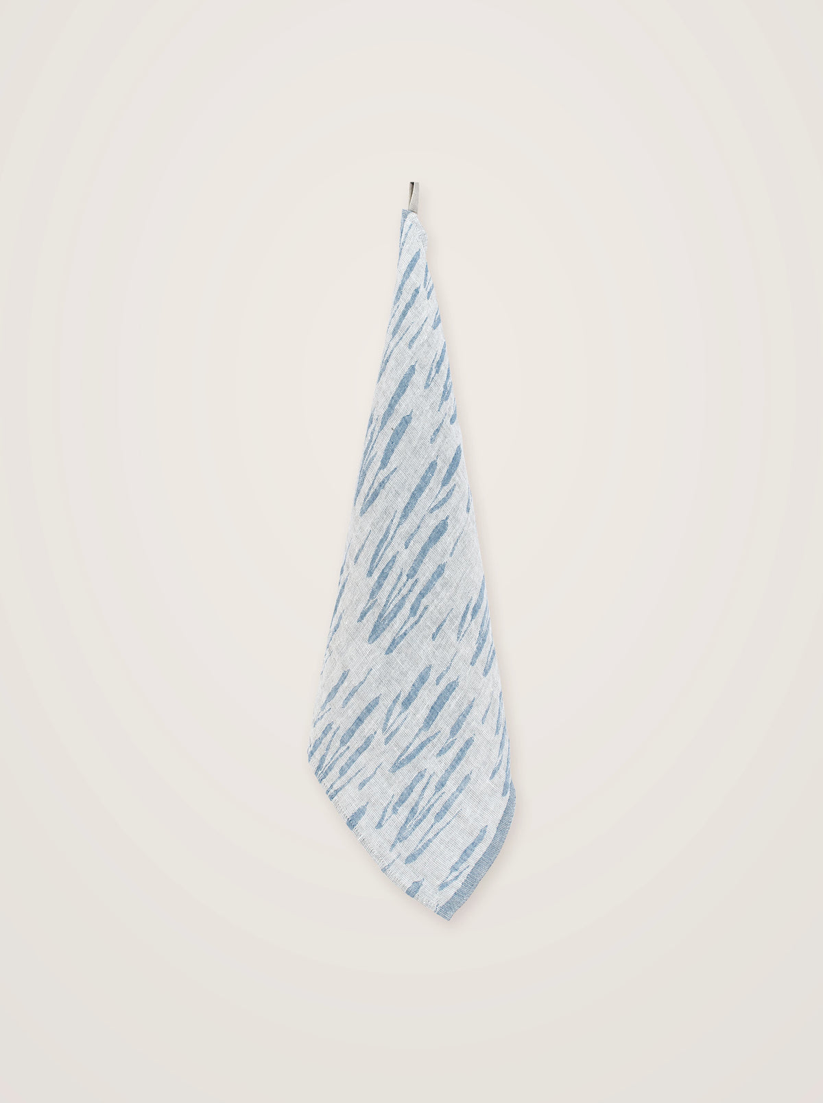 Washed linen towel with blue pattern hanging draped from a hook