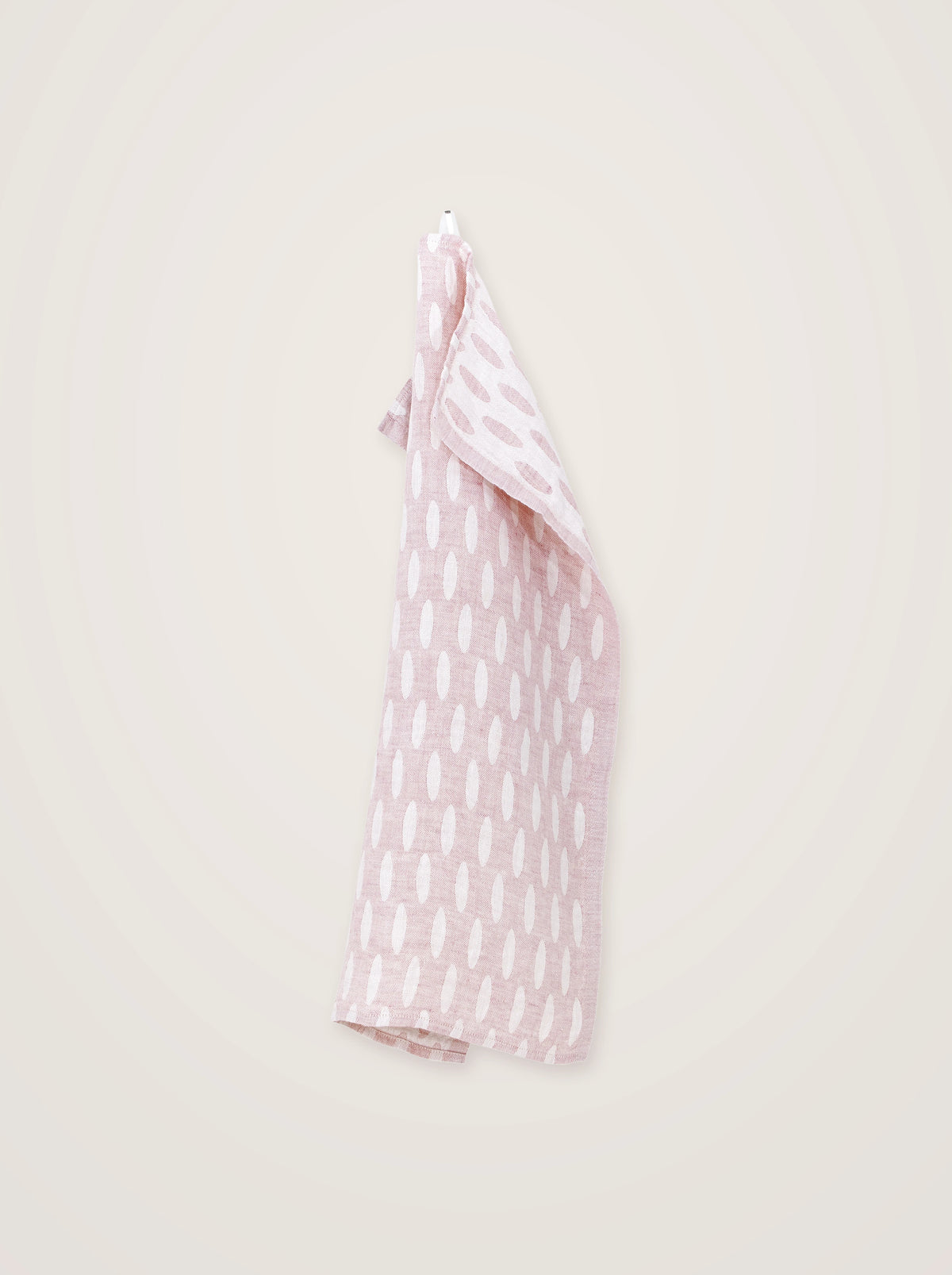 Washed linen towel in rose and white, hung to display the drape and the reversed pattern on the fold