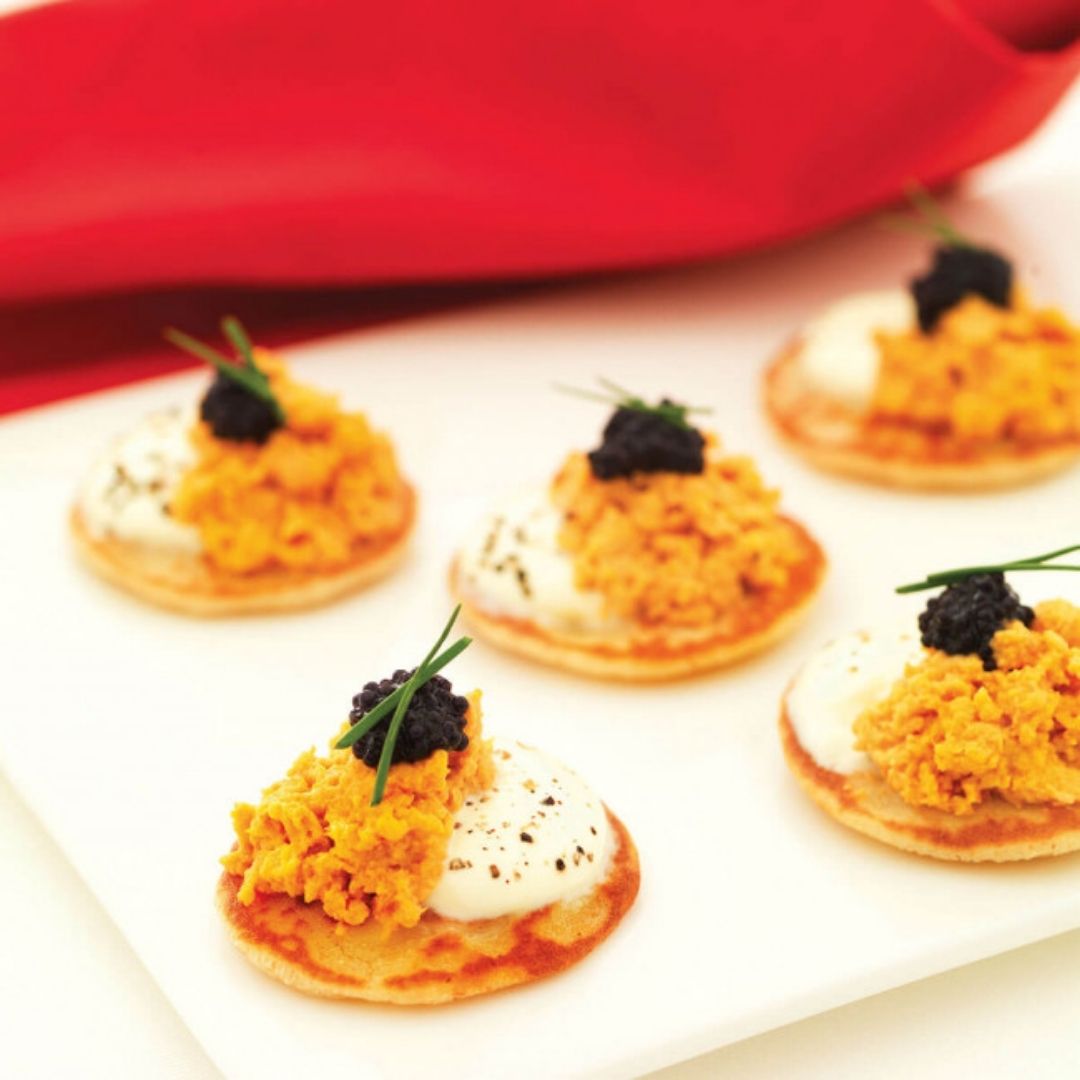 Canapés topped with lobster mousse, cream, black caviar, and chives