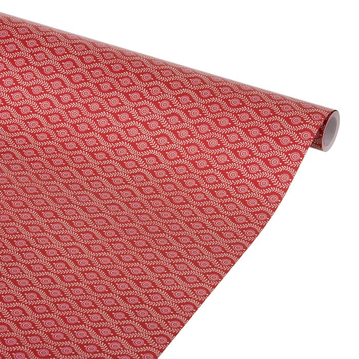 Scarlet wrapping paper roll partially unrolled, showing an intricate repeating white pattern