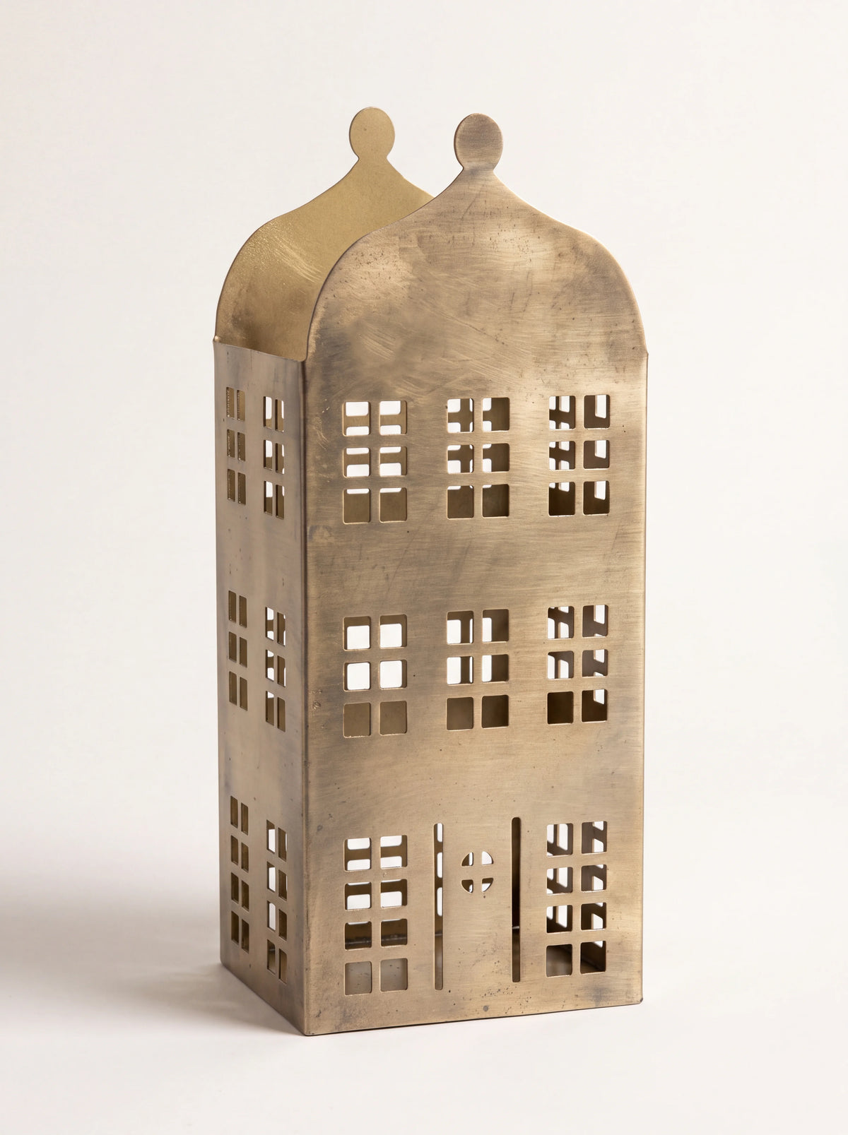 Brass-finish iron townhouse candle holder with cut-out windows and decorative curved gable