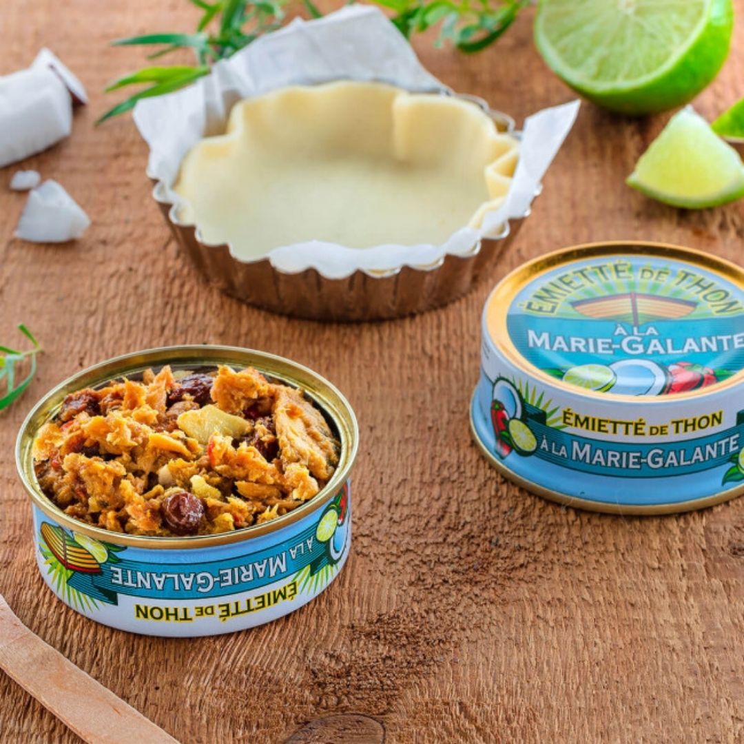 Open tin showing the spiced flaked tuna filling, beside an unopened tin and a tartlet crust