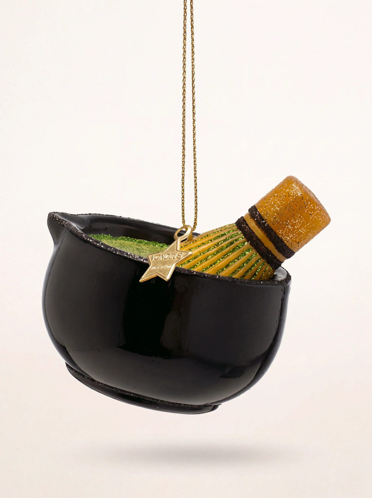 Glass matcha tea set ornament featuring a black bowl, green tea and a whisk, hanging from a gold cord