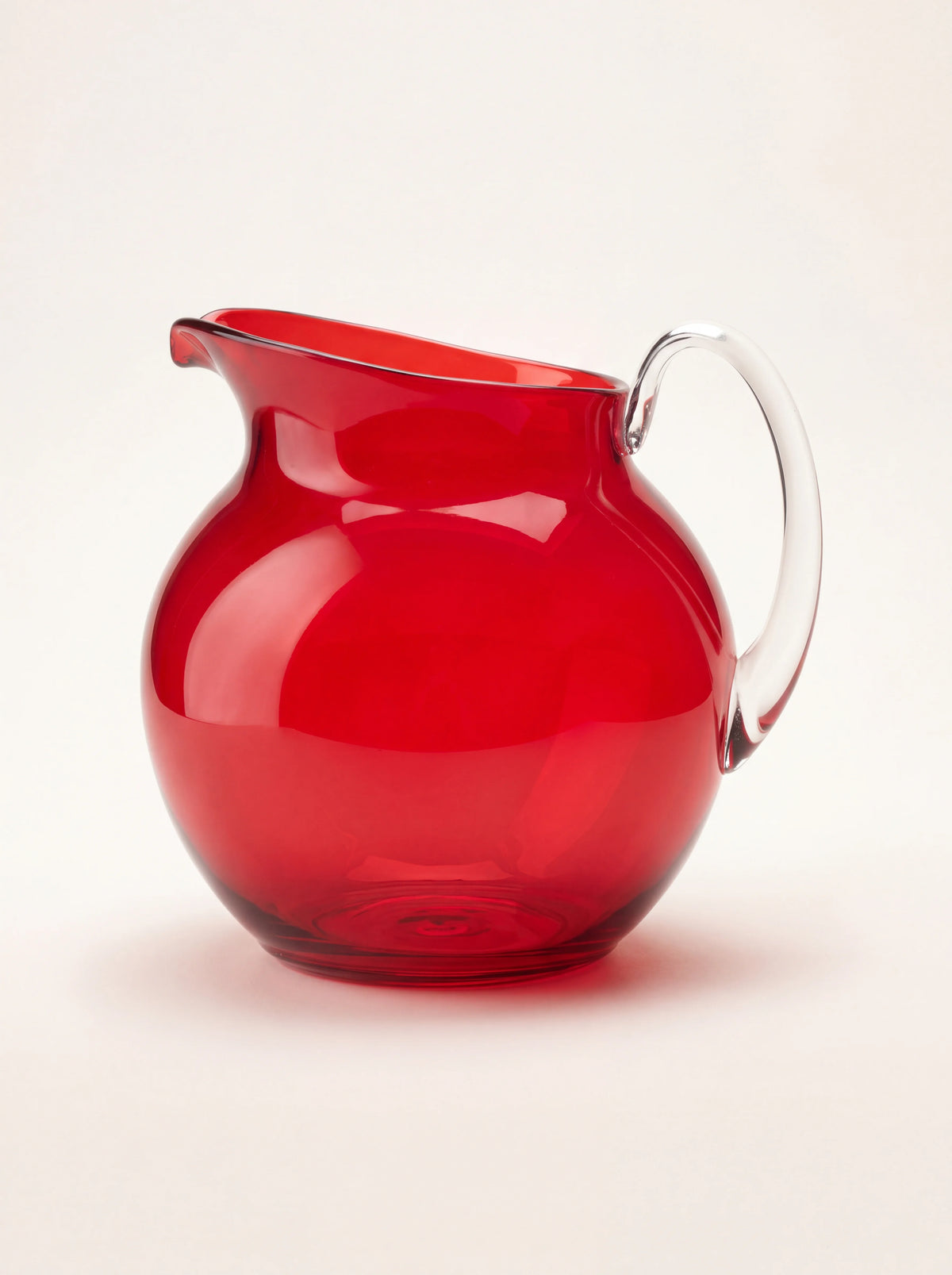 Spherical red acrylic pitcher with a clear curved handle and pouring spout