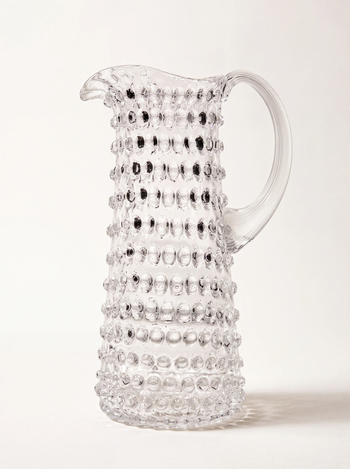 Clear glass jug with a raised hobnail texture, tapered silhouette and arched handle