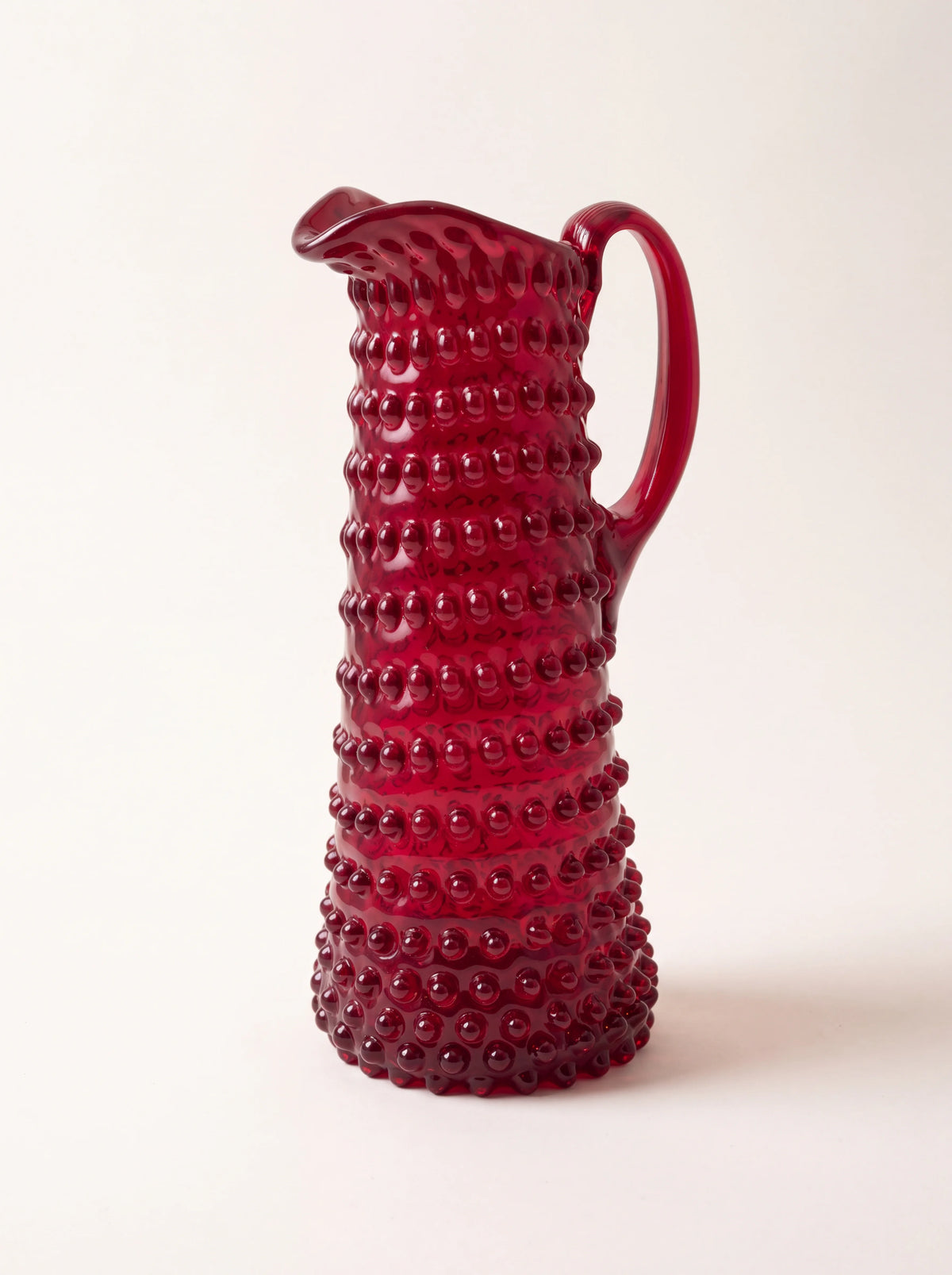Garnet red hobnail glass jug with a tapered body, curved handle and pouring spout