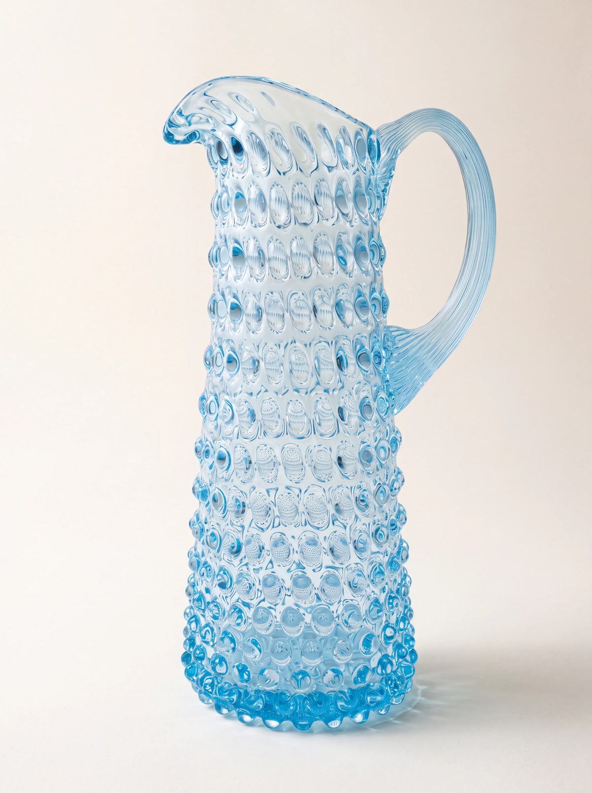 Light aquamarine hobnail glass jug with a tapered body, pouring spout and arched ribbed handle