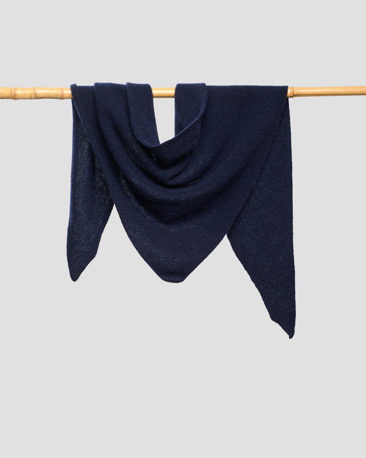 Navy merino wool bandana draped over a wooden pole, showing its triangular shape and fine weave