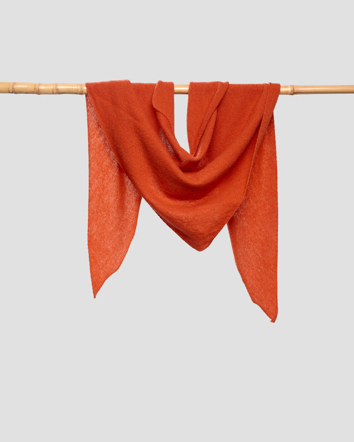 Orange merino wool bandana draped over a rail, showing the fine weave
