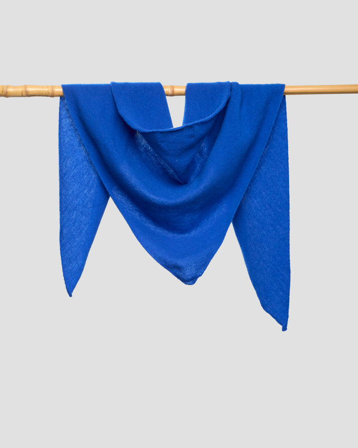 Royal blue merino wool bandana draped over a wooden rail, showing its drape and weave