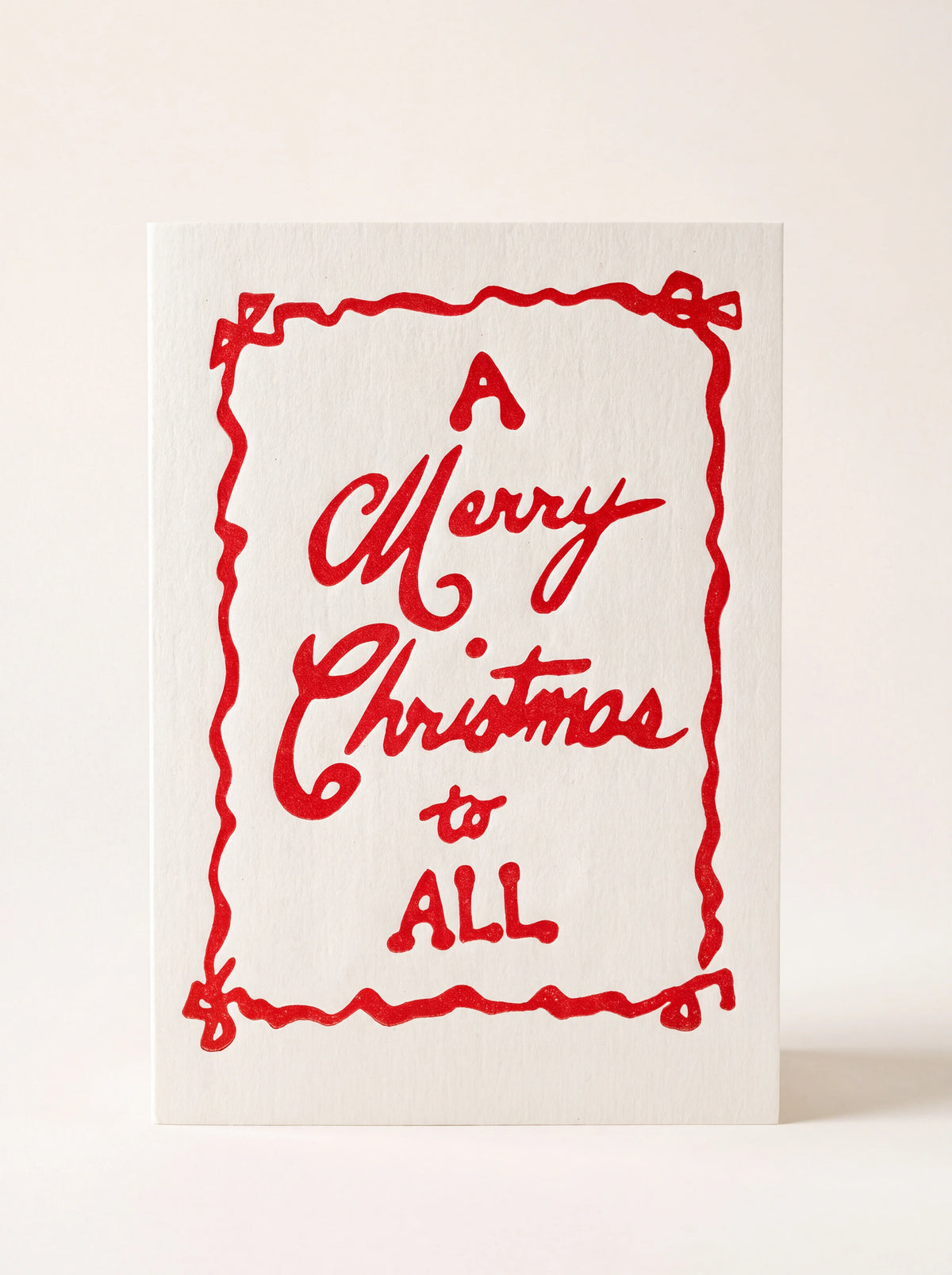 Paper Christmas card with a red ribbon border and text reading 'A Merry Christmas to ALL