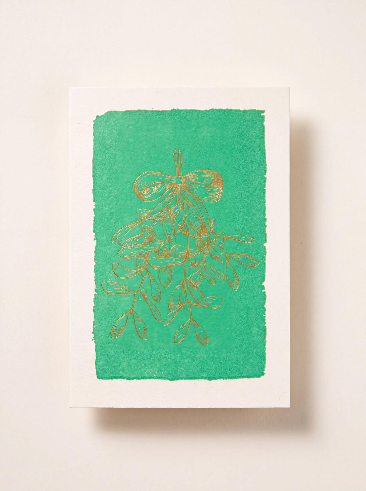 Paper greeting card with a gold-tone mistletoe illustration on a green panel with a white border