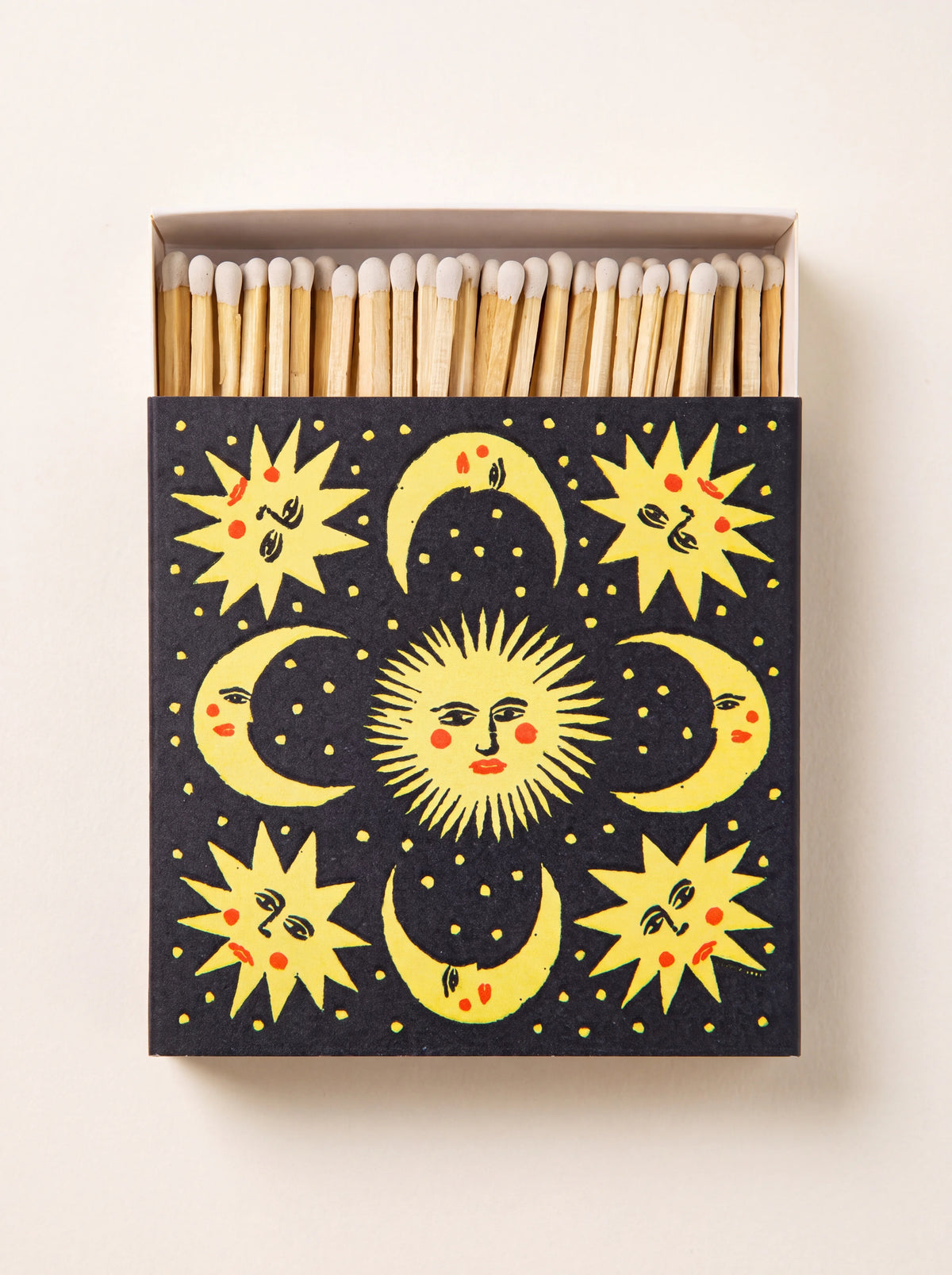Square black matchbox with yellow celestial sun and moon illustrations, opened to show white-tipped matches