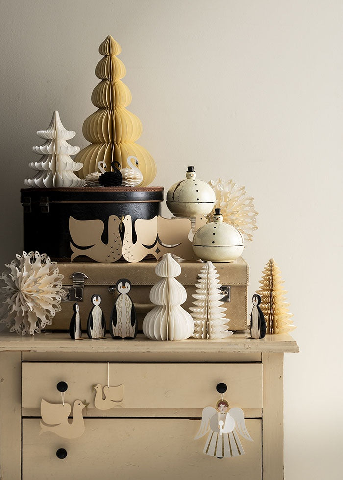 Cream honeycomb tree styled on a case alongside festive figurines and paper ornaments