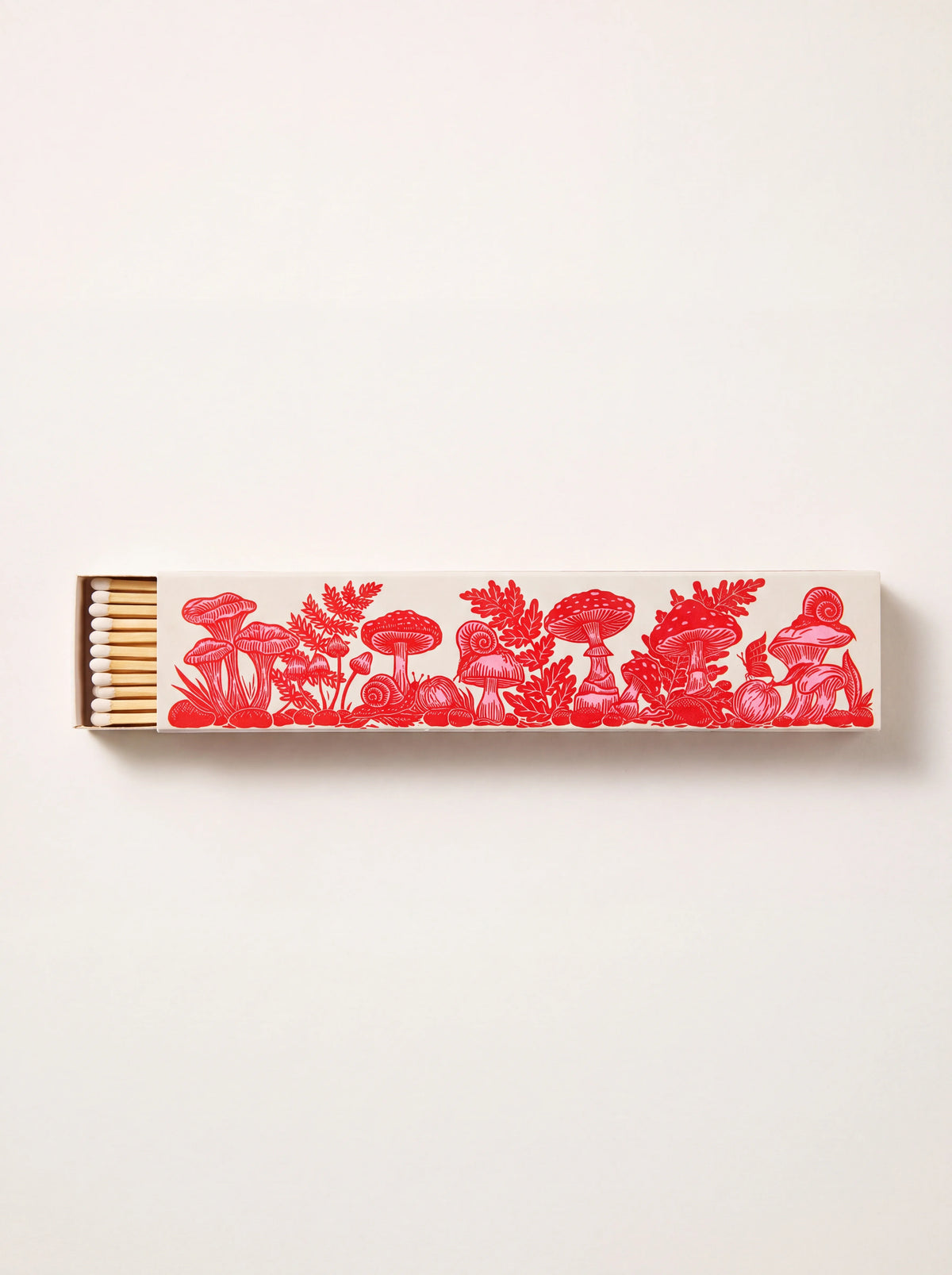 Long matchbox printed with red mushroom illustrations, partially open to reveal white match tips