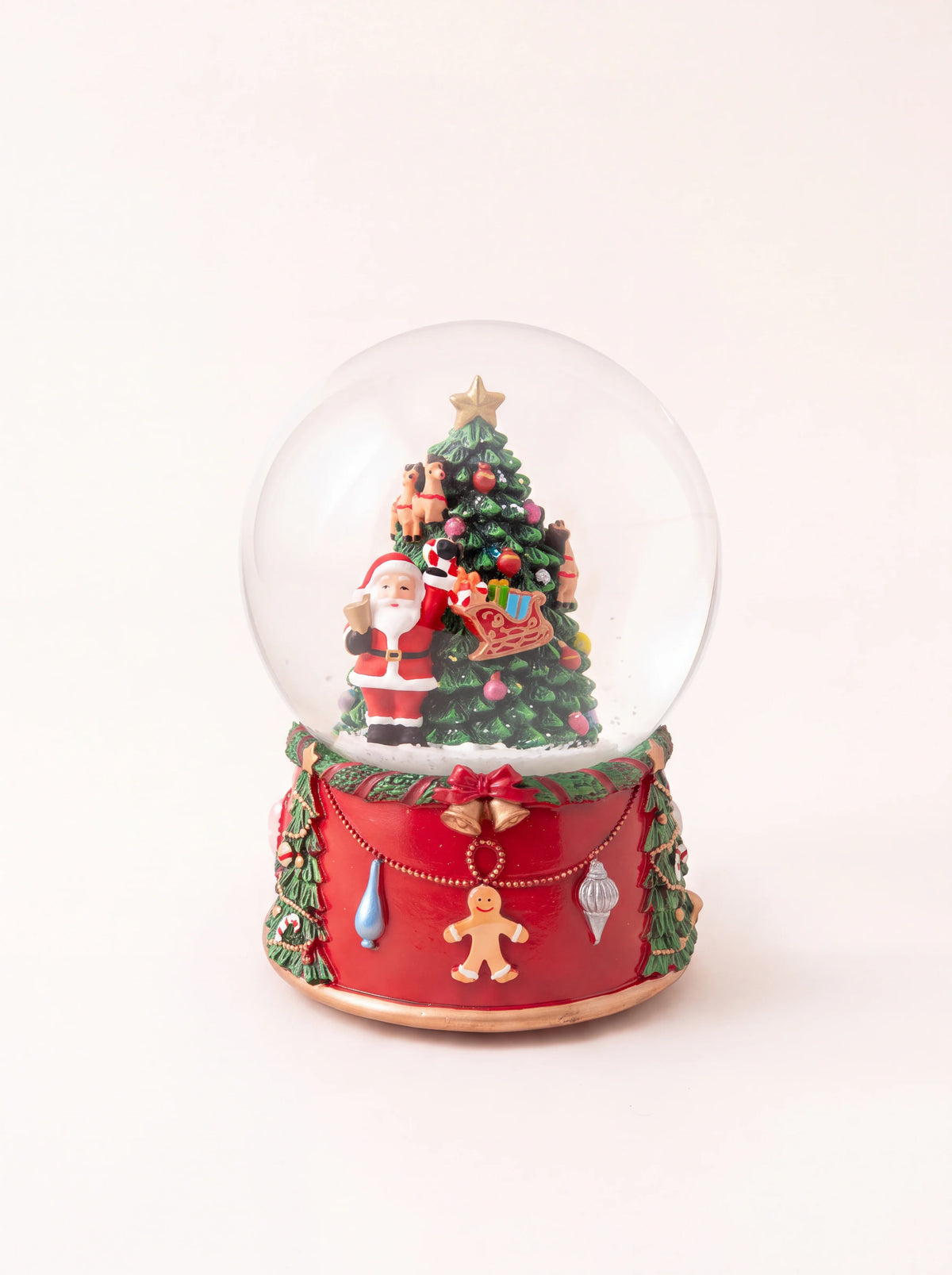Musical snow globe with Santa Claus and a decorated tree, on an ornate red base with hanging ornaments