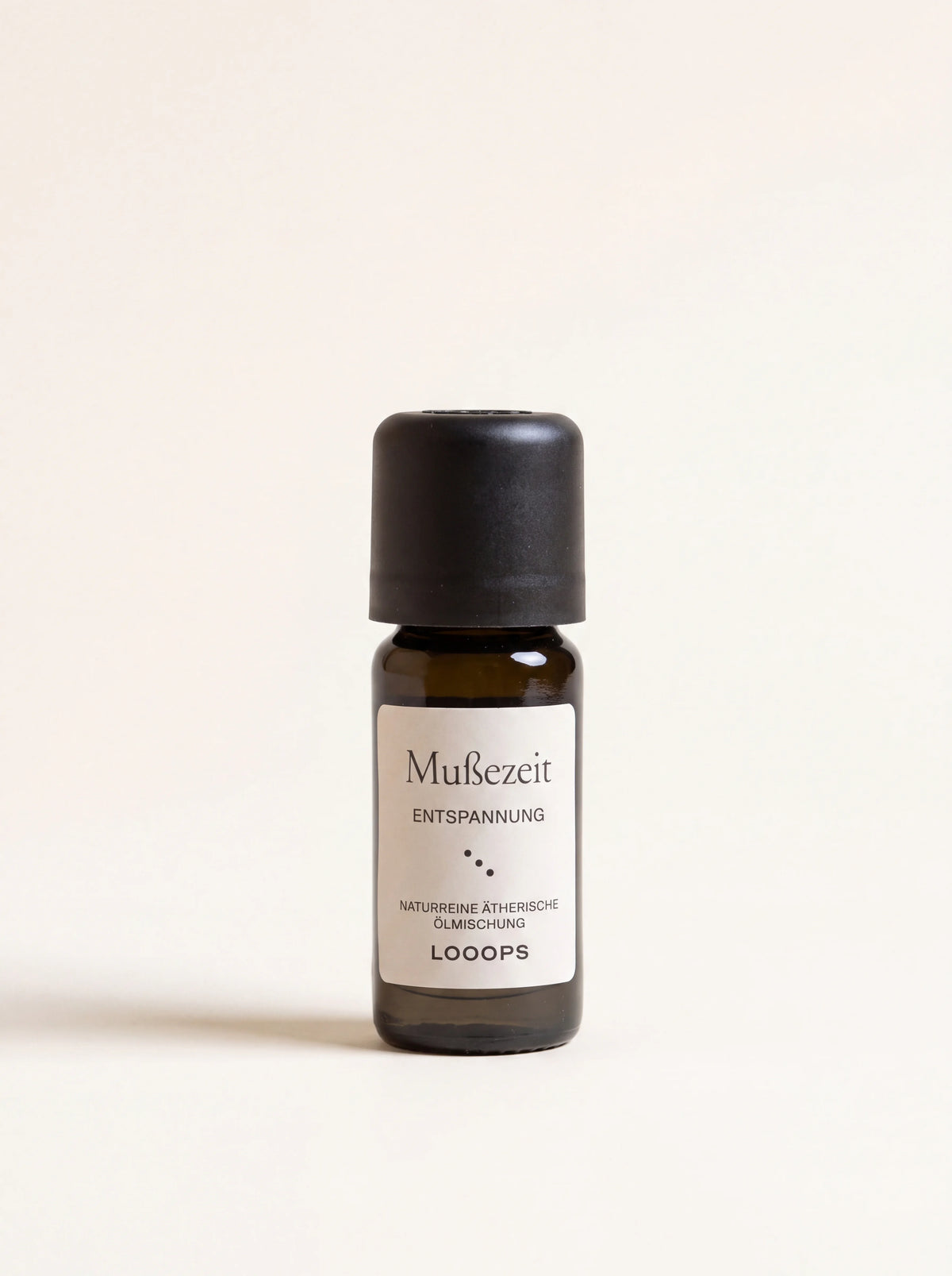 Amber glass essential oil bottle with a black cap and white label reading Mußezeit ENTSPANNUNG