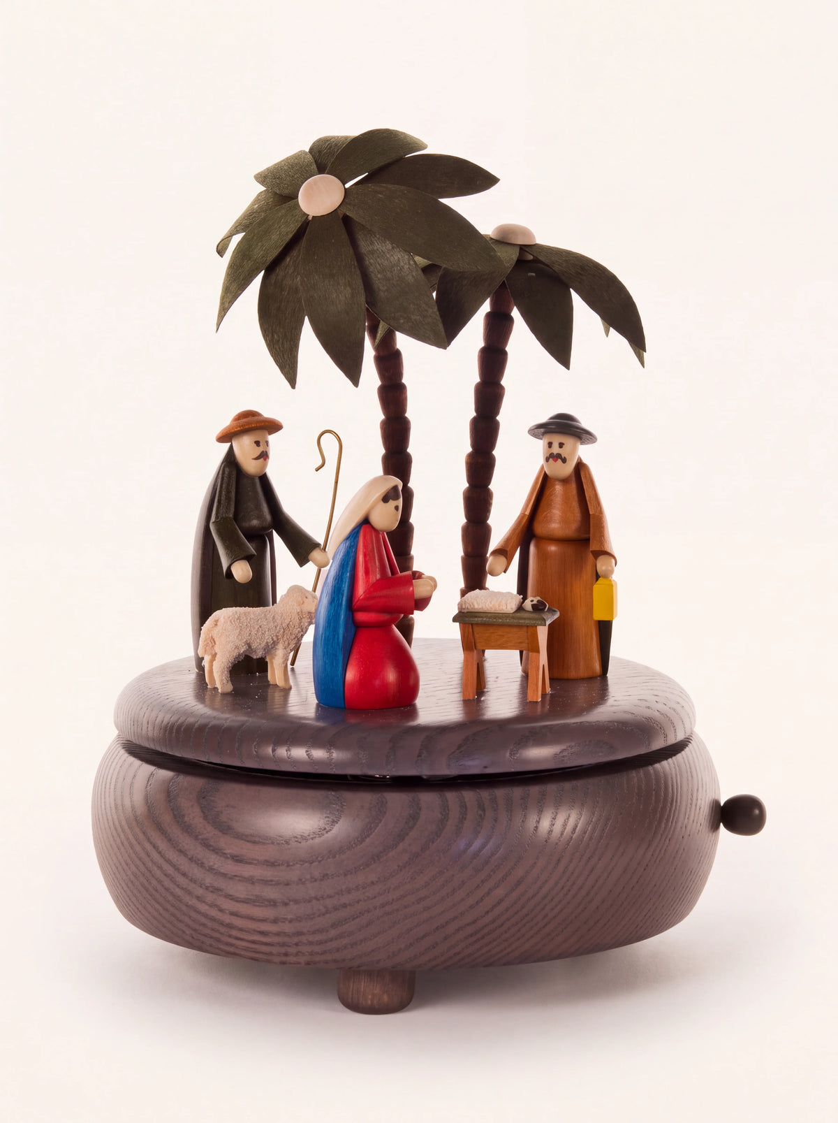 Grey wooden music box with turned Nativity scene figures and palm trees on a footed round base