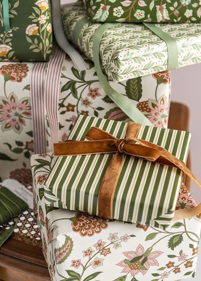 Gift wrapped in the botanical leaf paper and tied with ribbon, stacked among other presents