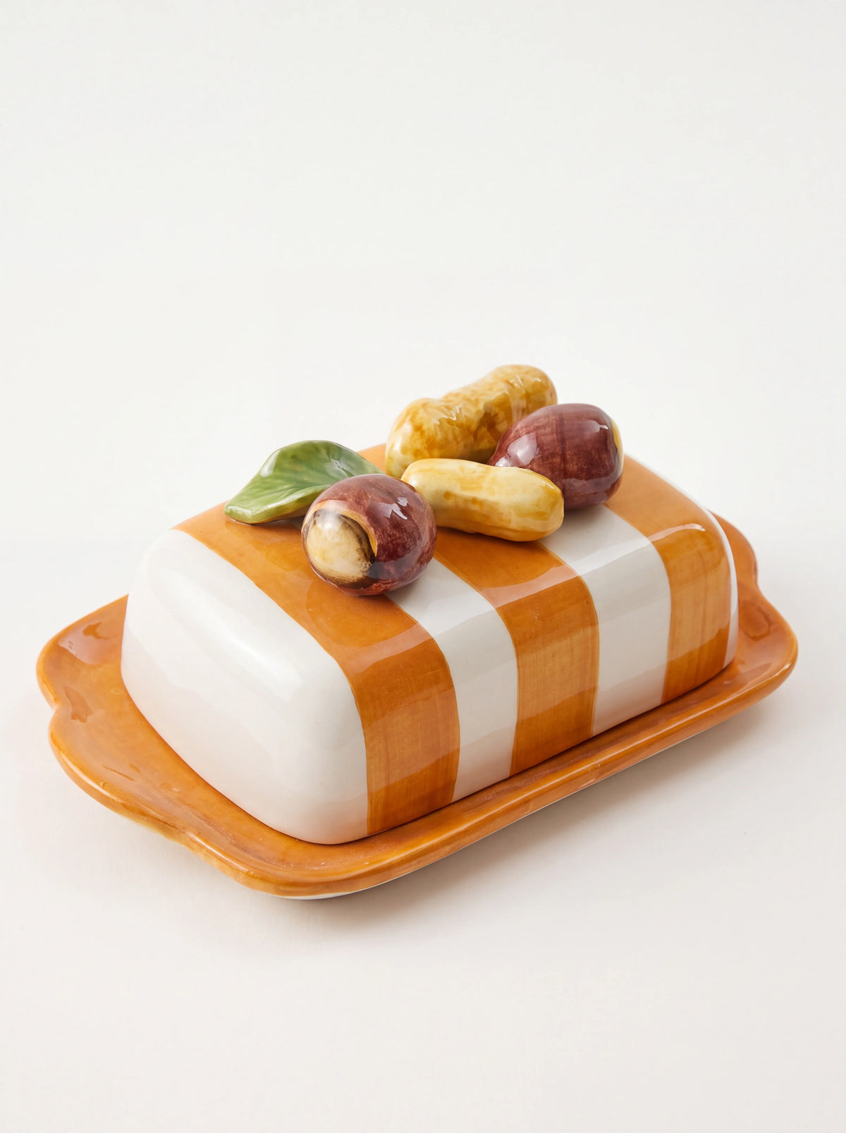 Striped ceramic butter dish with an orange and white domed lid, sculpted nut handle, and orange base plate