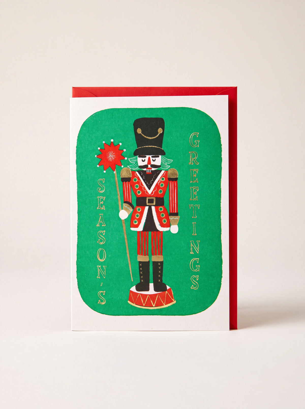 Greeting card featuring a nutcracker illustration and gold Season's Greetings text, with red envelope