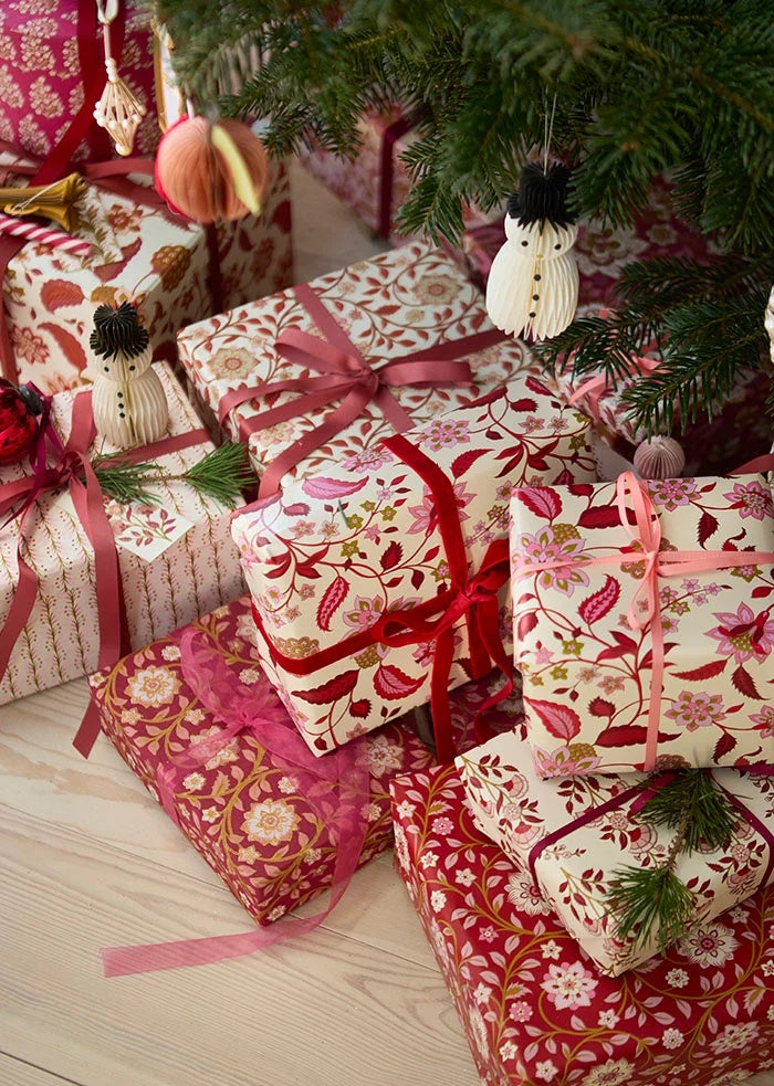 Sheer organza ribbon tied in a loose bow around a patterned present beneath Christmas tree branches