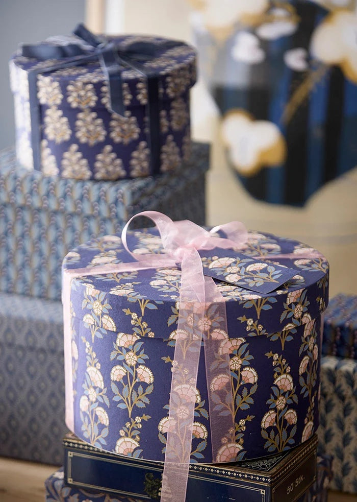 Light pink organza ribbon tied in a bow around a round floral gift box