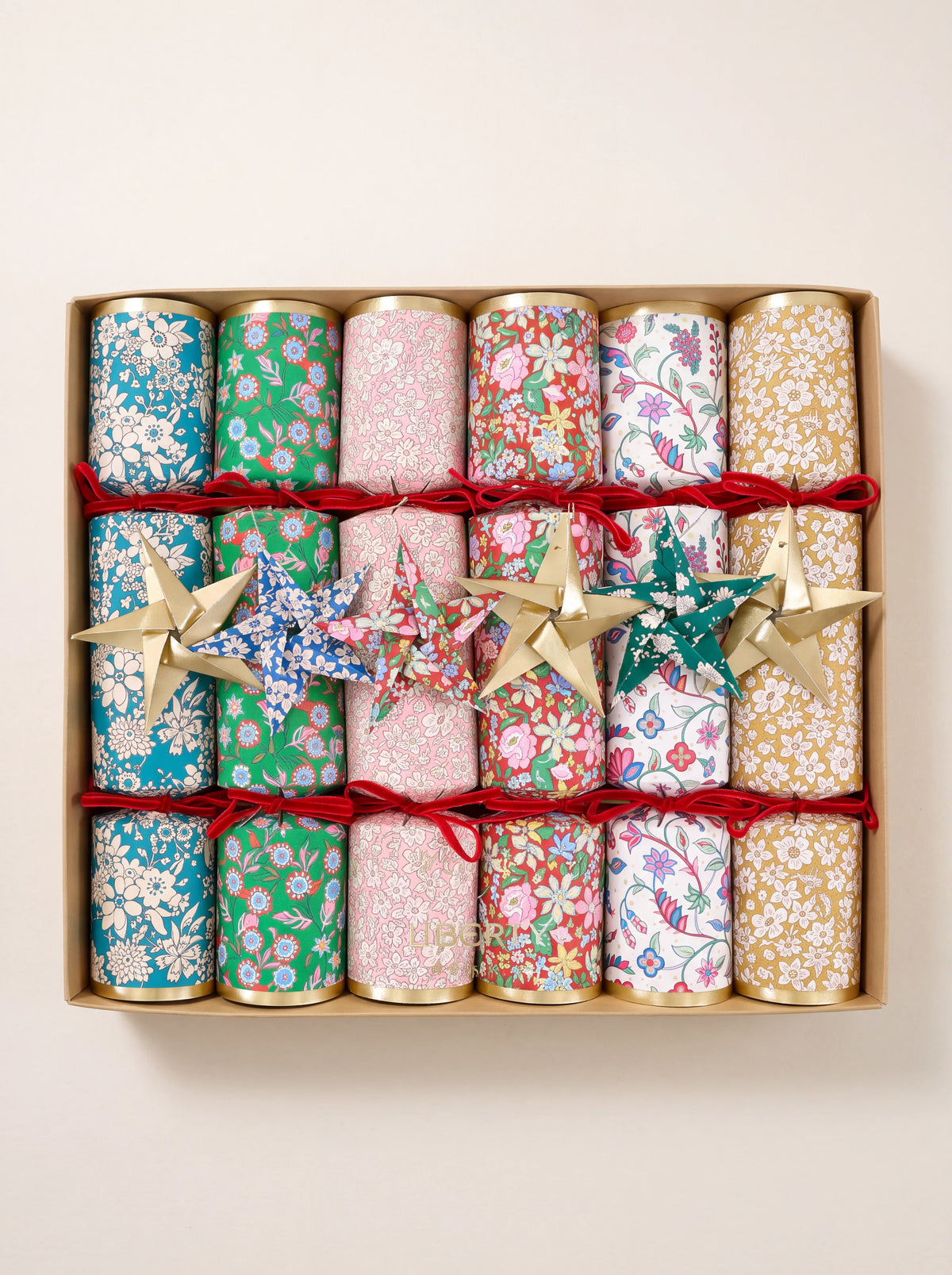 Paper crackers in a set of six, featuring floral patterns, red velvet bows, and attached origami stars