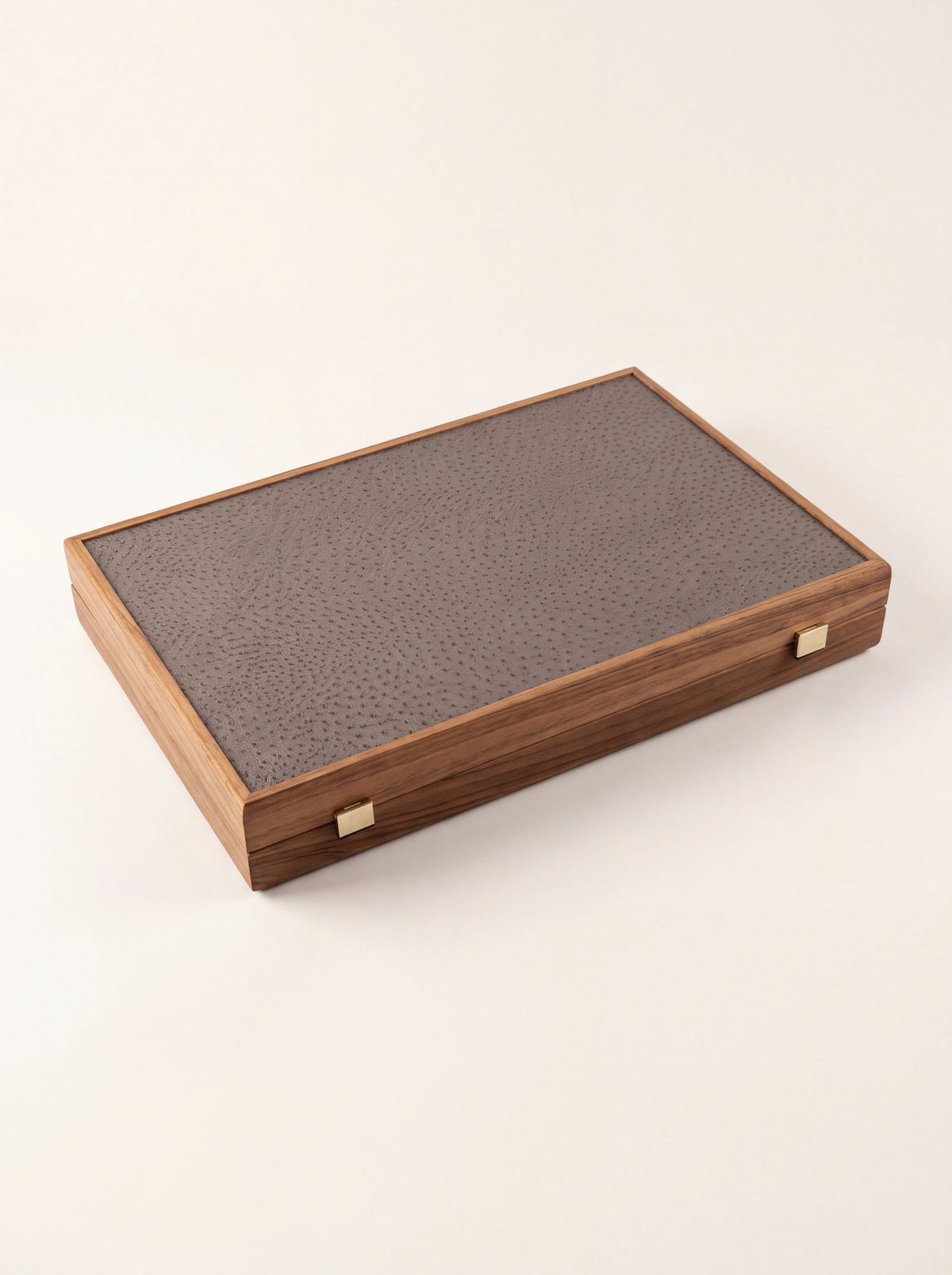 Closed backgammon case showing the ostrich-textured faux-leather panel and metal clasps
