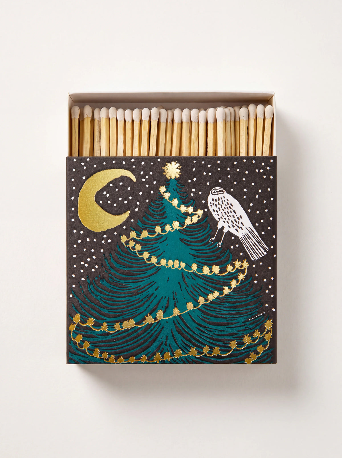 Square matchbox open to show matches, printed with a white owl perched on an evergreen tree under a gold crescent moon