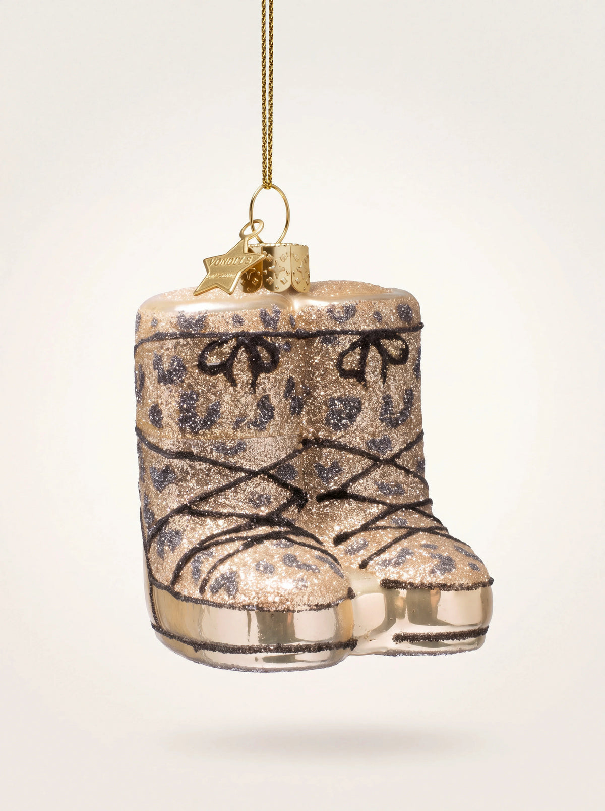 Glass snow boots ornament in champagne glitter with a panther pattern and decorative laces