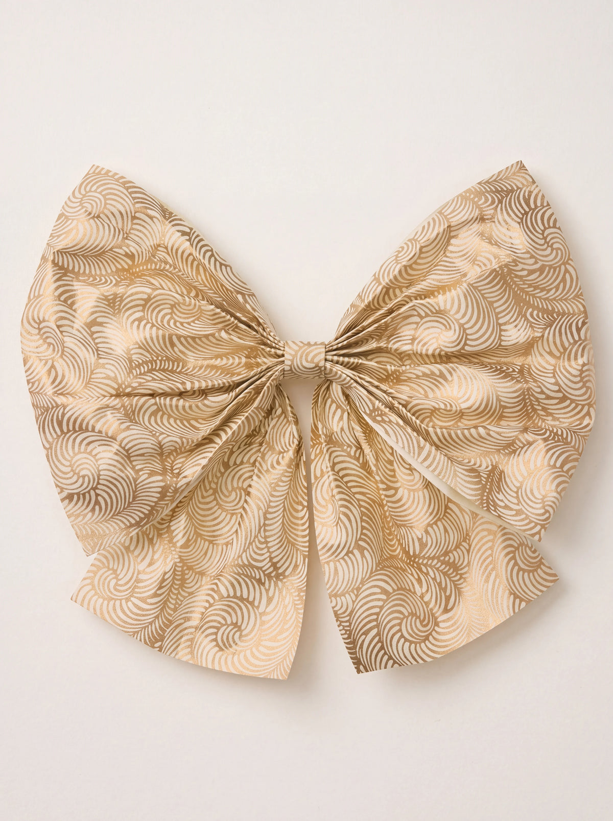 Pleated cotton paper bow in cream with a swirling gold pattern