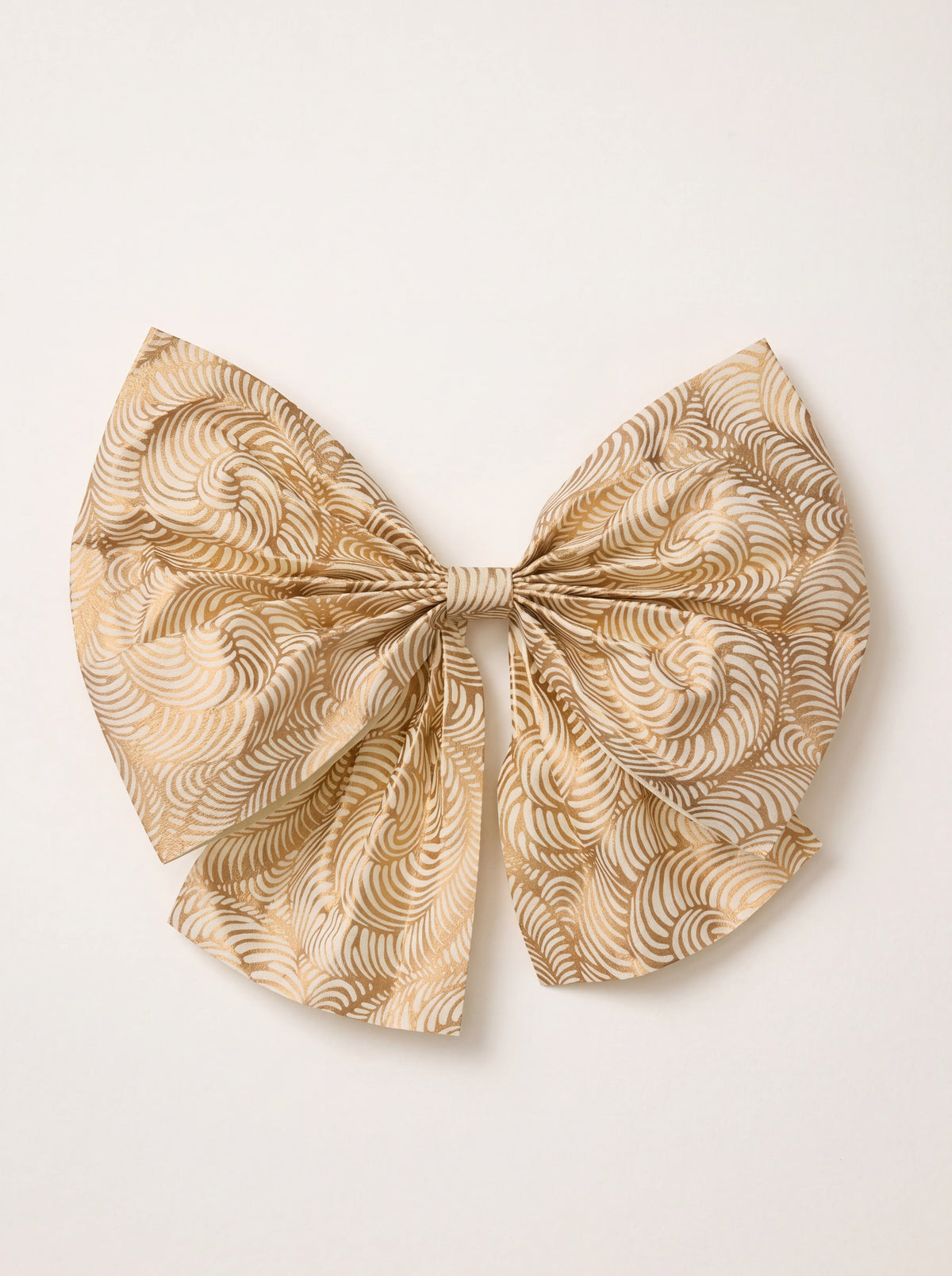 Decorative bow in cream cotton paper with a metallic gold swirling pattern