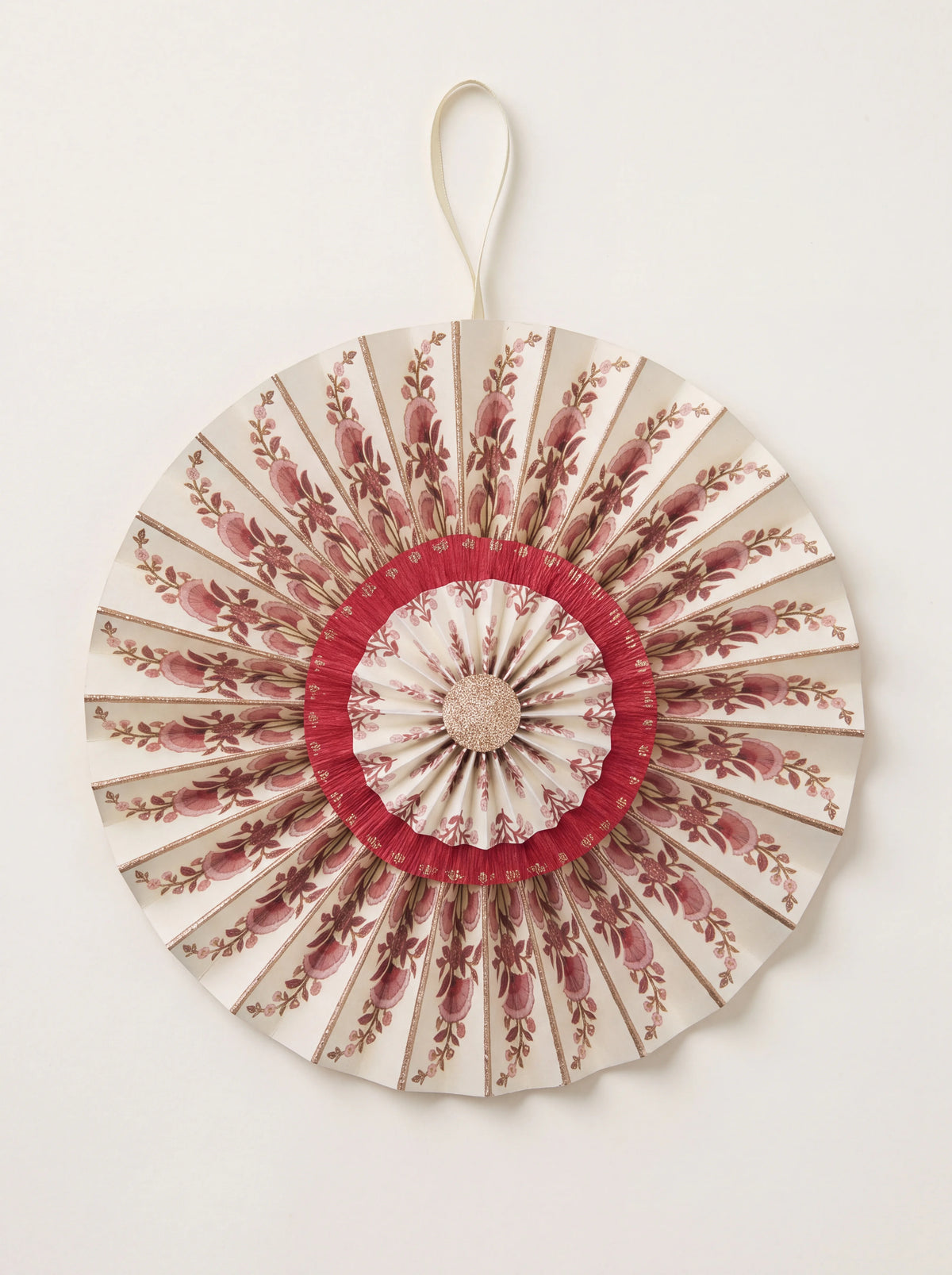 Pleated cotton paper rosette with floral berry print, red accents, glitter details and a ribbon hanging loop