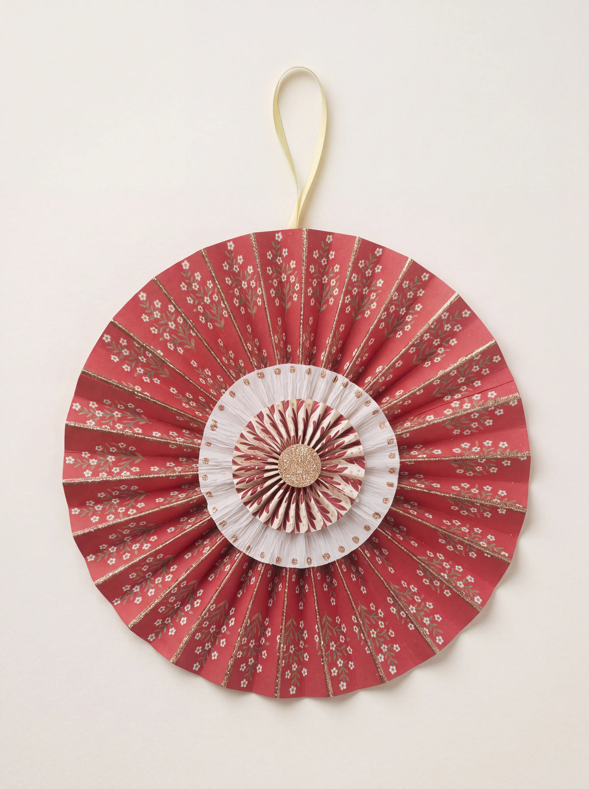 Pleated scarlet cotton paper rosette with concentric floral tiers, glitter accents, and a ribbon hanging loop