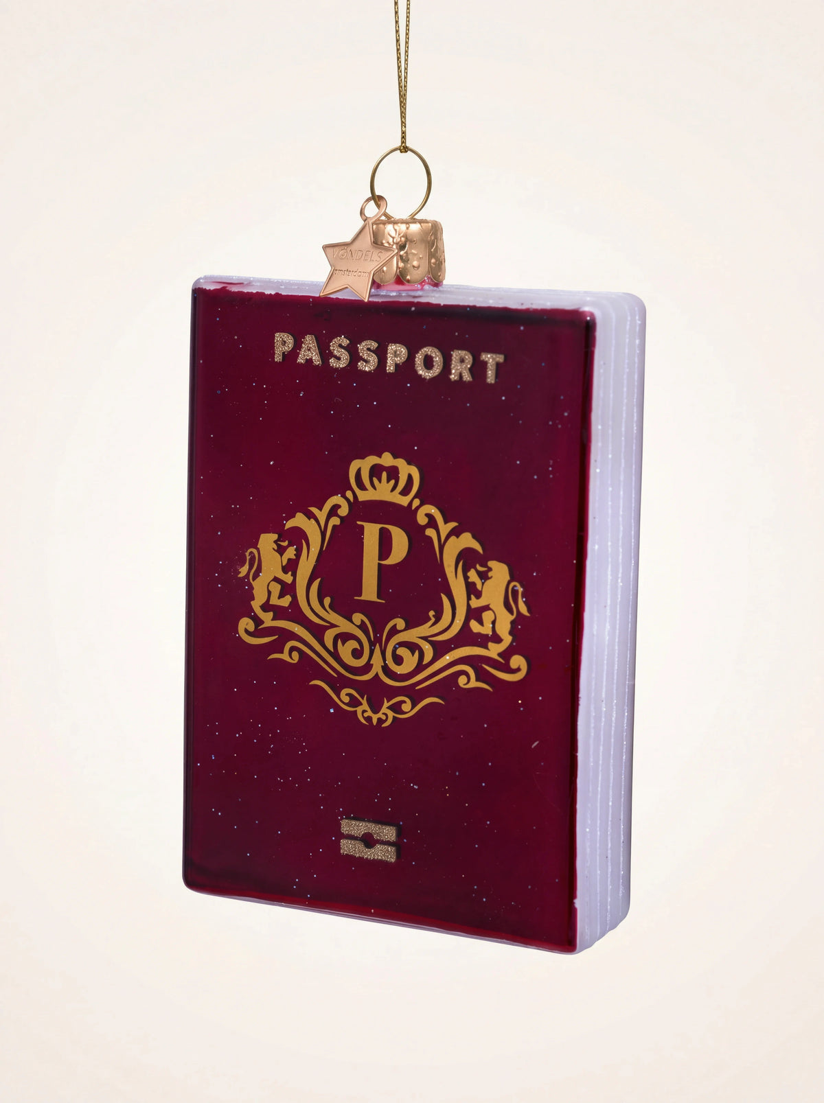 Red glass passport ornament with gold lettering, an ornate crest, and glittered page edges