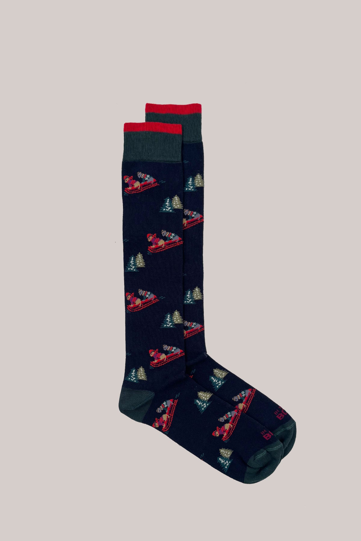 Dark blue knitted socks with dogs sledging among pine trees, featuring red and green ribbed cuffs