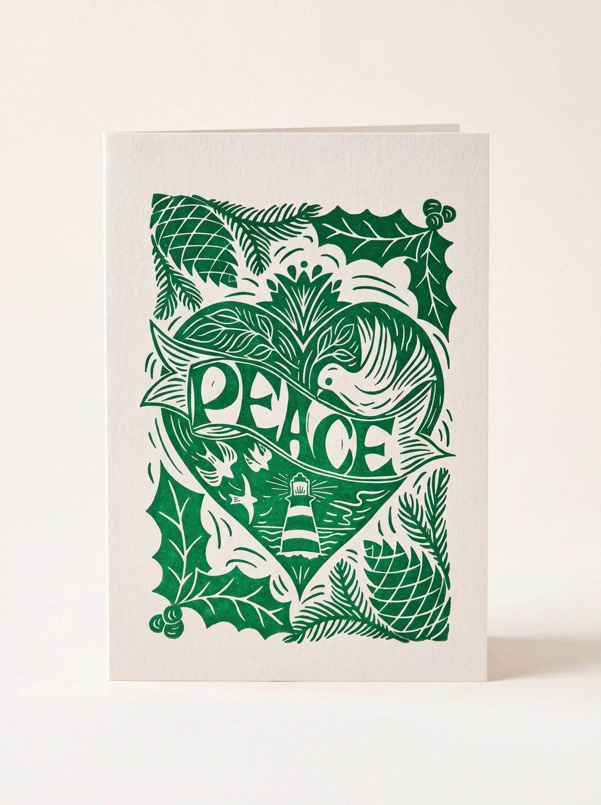 Paper greeting card with a green linocut illustration of a heart, dove, lighthouse, and the word PEACE