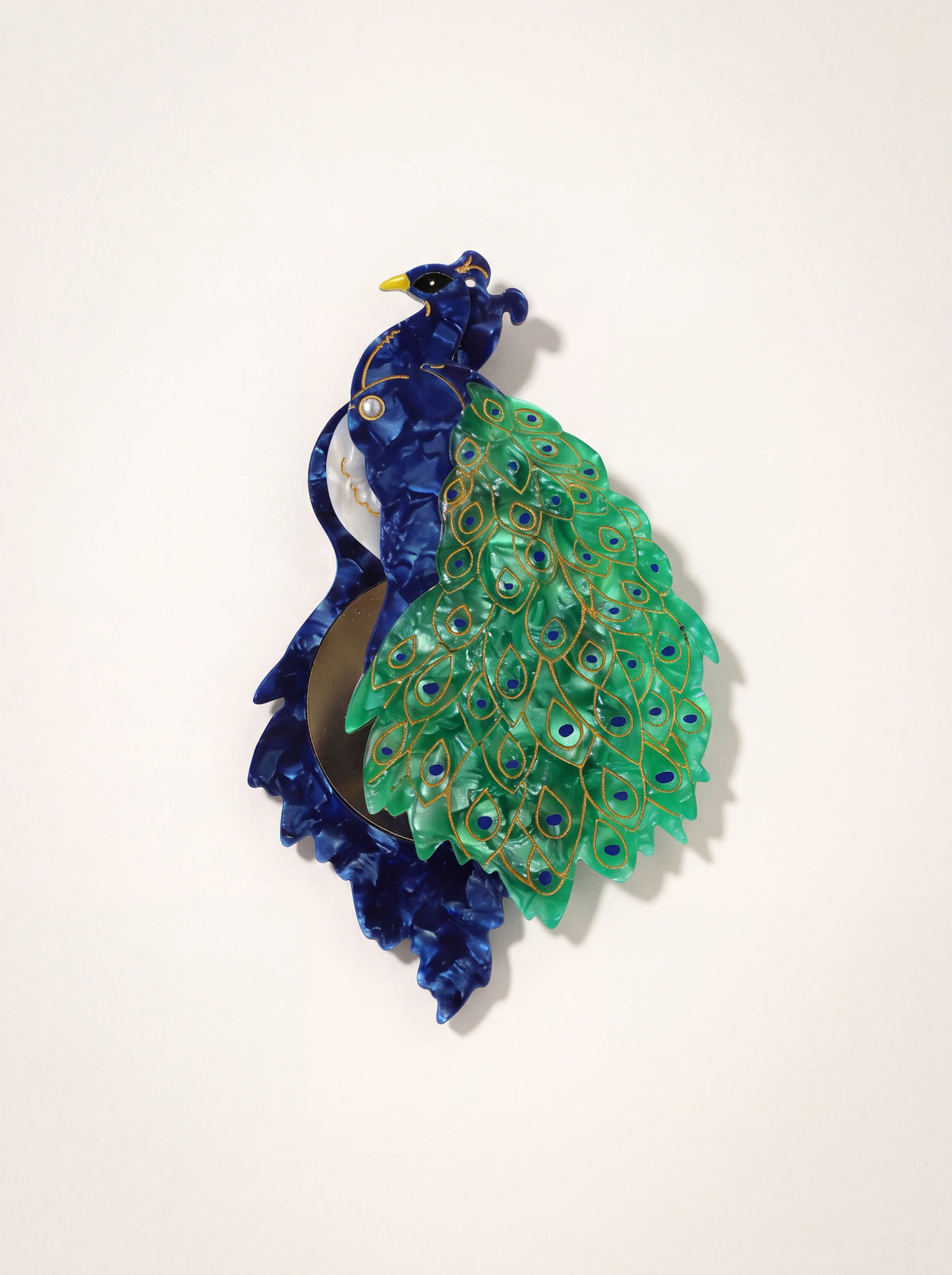 Peacock compact mirror in blue and green cellulose acetate, swivelled open to show the round mirror