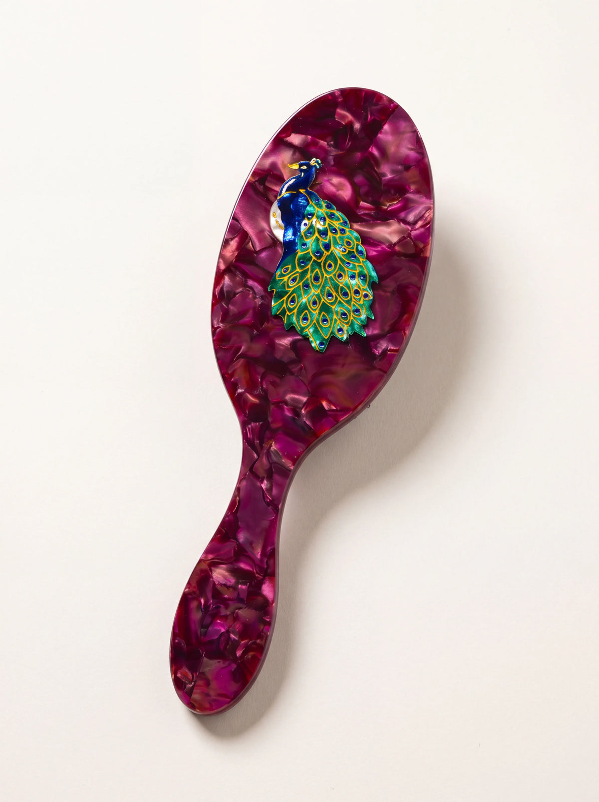 Oval purple acetate hairbrush with a marbled finish and a hand-painted blue and green peacock motif