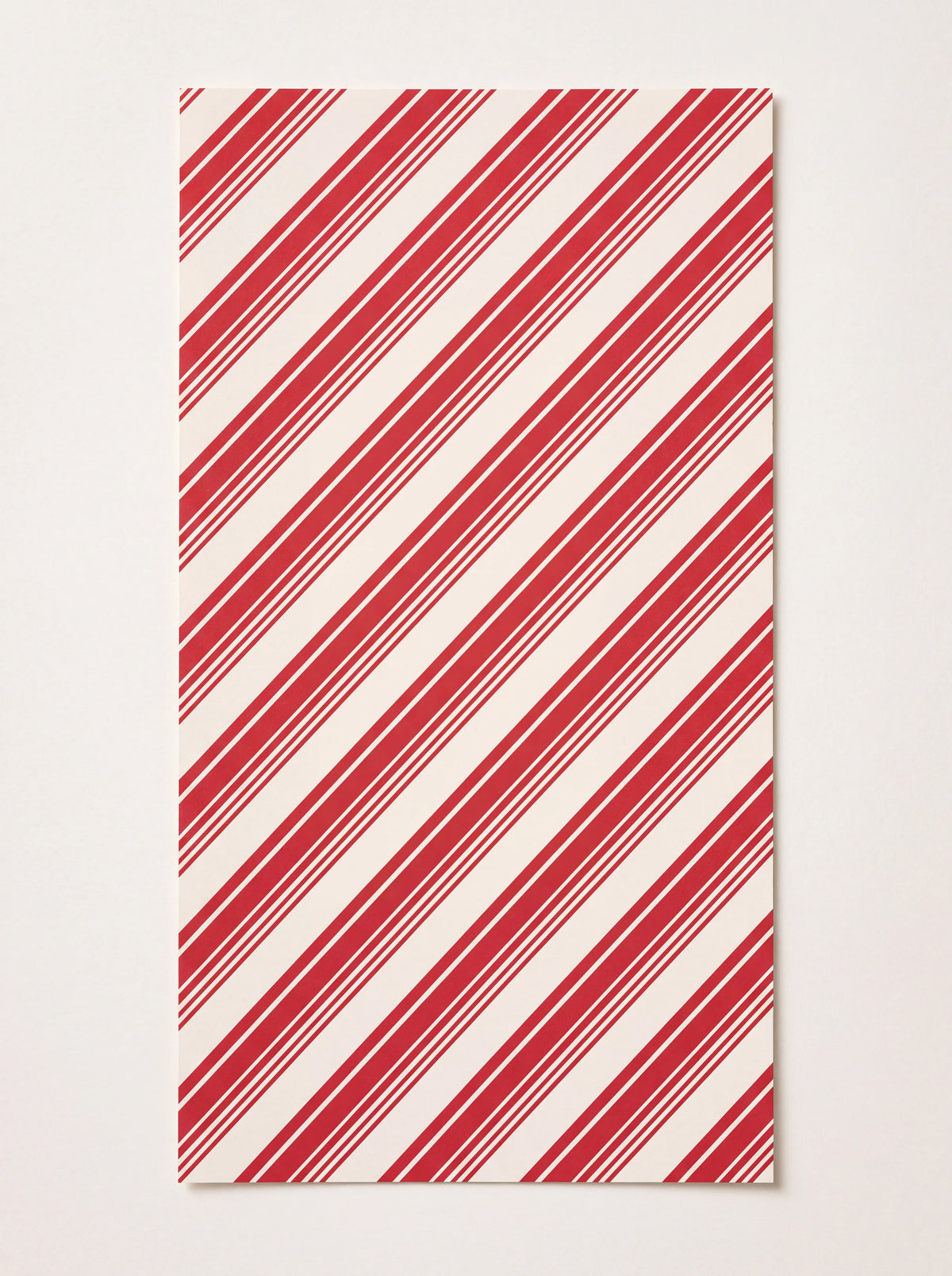 Rectangular paper guest napkin with diagonal red and white peppermint stripes