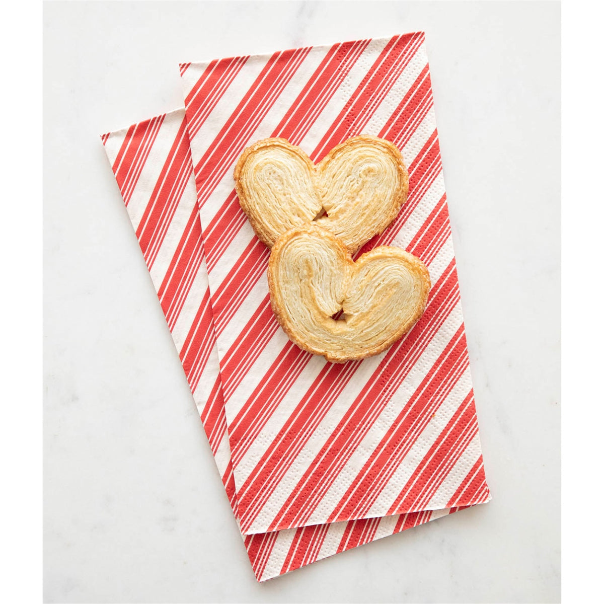 Two overlapping red striped guest napkins topped with palmier biscuits, showing embossed edges