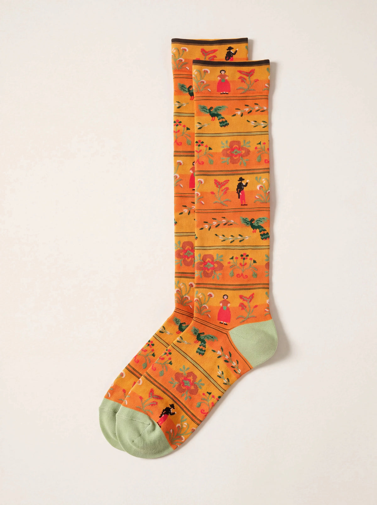 Amber knee-high cotton socks patterned with figures, birds and floral bands, with pale green heels and toes
