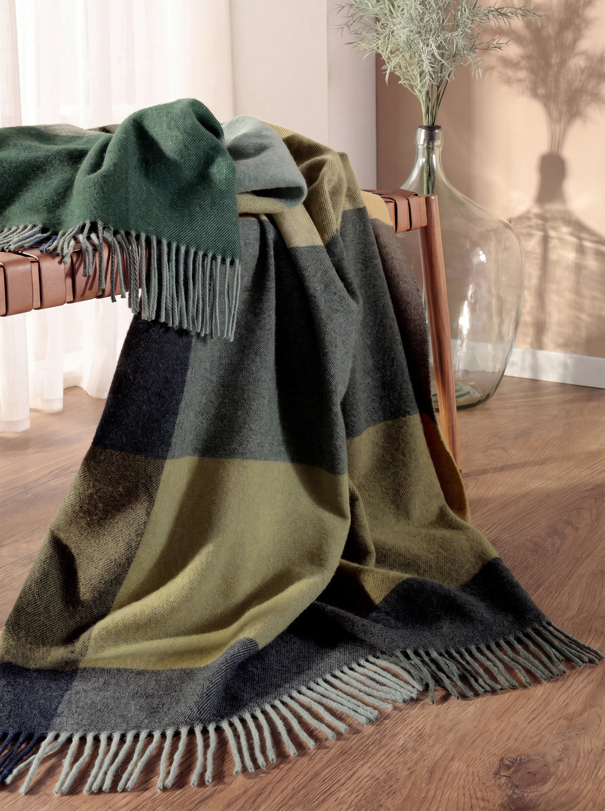 Wool and cashmere blanket draped over a bench, showing its texture and fringe against the floor