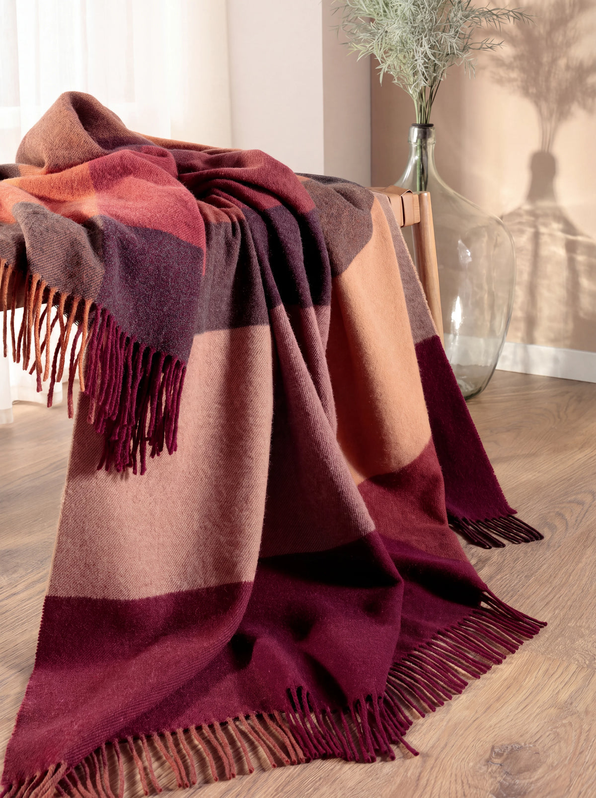 Wool and cashmere blanket draped over a chair, revealing the full colour-block pattern and fringed ends