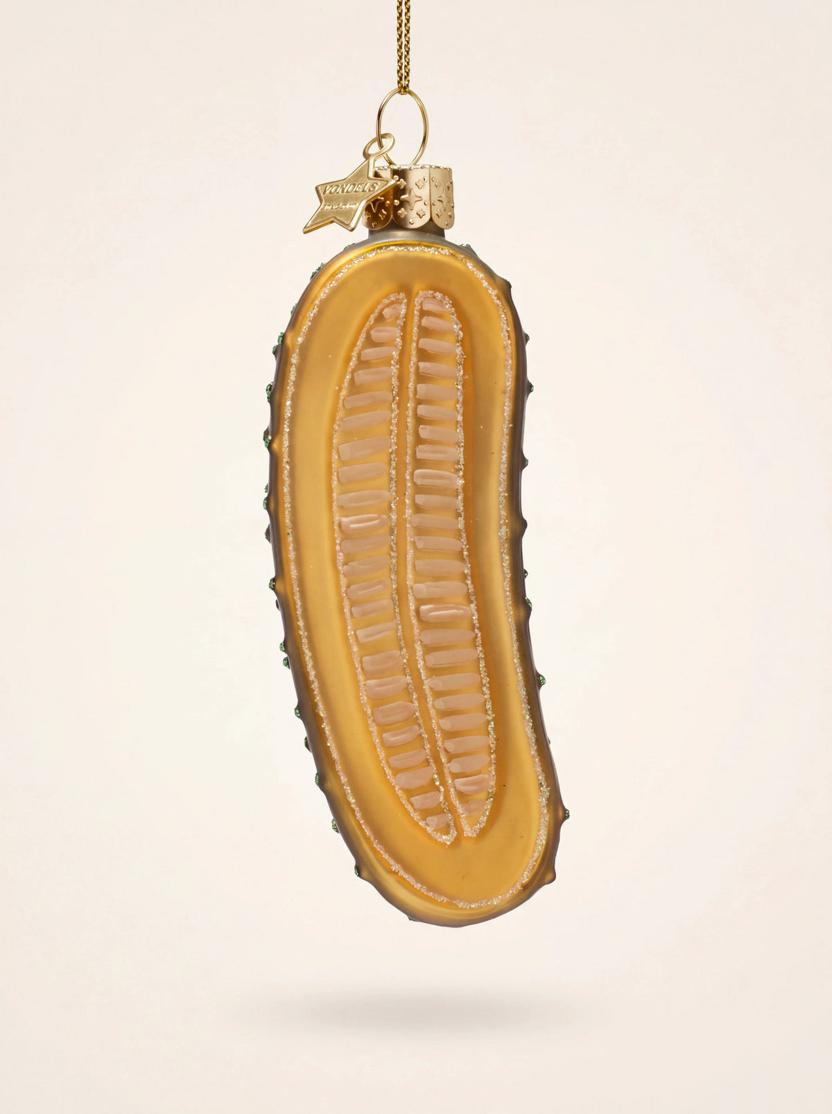 Pickle slice glass ornament showing hand-painted yellow interior with seed rows and glitter trim